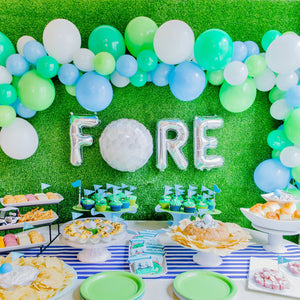 Golf balloon garland in white, lime, spring green, and light blue colors used for golf party decor with balloons spelling FORE.