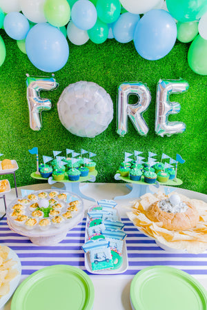 Golf balloon garland in white, lime, spring green, and light blue colors used for golf party decor with balloons spelling FORE.