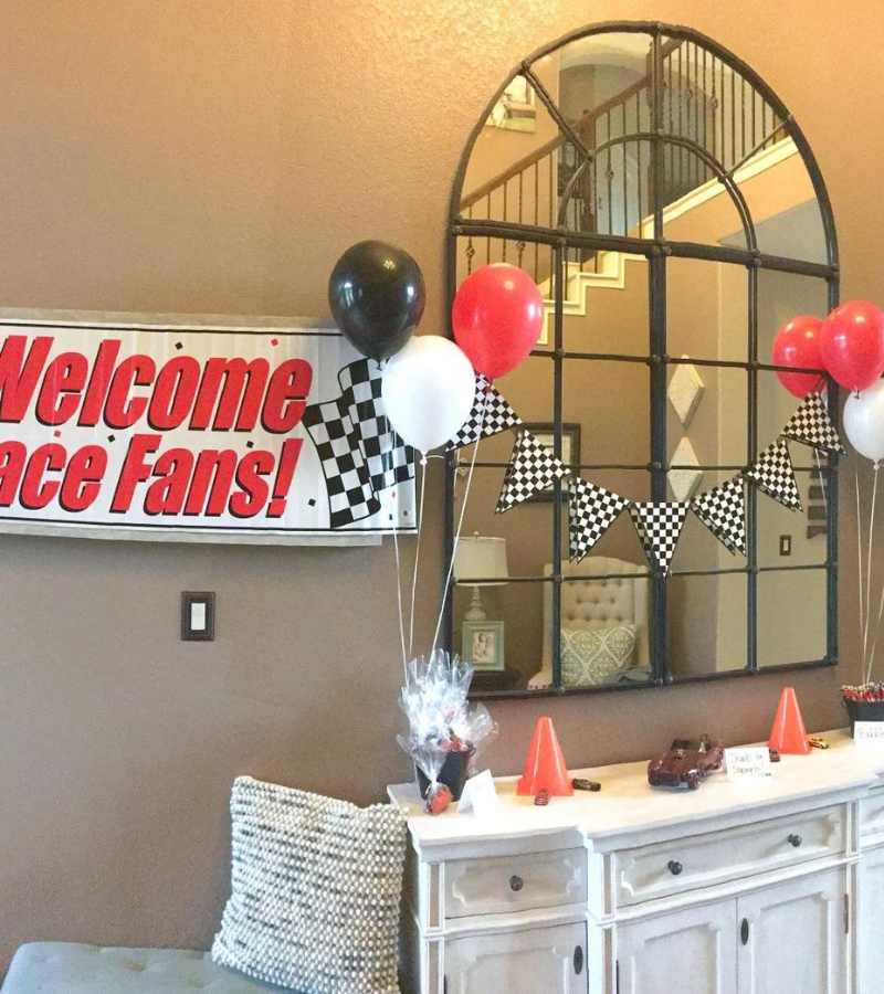 A racecar themed party with red, black, and white balloons floating with helium