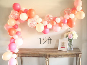 A size example shows a 12 foot balloon garland made up of coral, pearl peach, rose, white, and matching confetti filled balloons sitting above a 6 foot table for comparison.