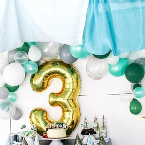 A gold mylar number 3 balloon in a birthday backdrop.
