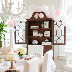 A china cabinet decorated with a balloon garland for a birthday party.