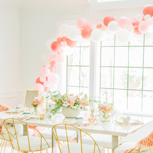 A cute event setup with a huge window decorated with a balloon garland in different shades of pink and white balloons.