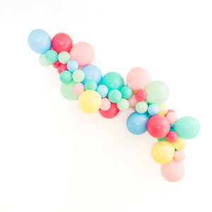 A balloon garland is draped on a white wall in light easter pastel style colors. Balloons are in the following the colors: pink, rose, pastel mint, pearl lemon, light blue, and aquamarine.