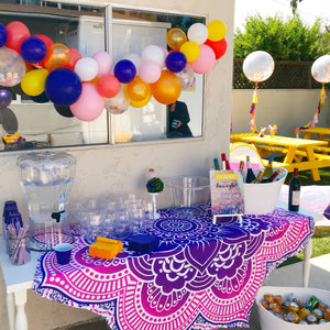 Bright and bold colored balloon garland hangs outside of a window at a party.