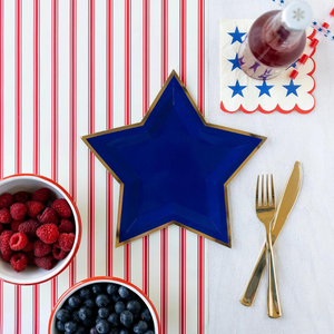 Blue star shaped gold foil plate with a bowl of blueberries sitting next to it and a bowl or raspberries.