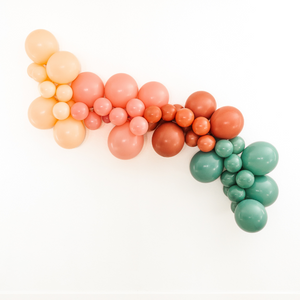 Balloon garland hung on wall with in the colors blush, mauve, terracotta, and willow.