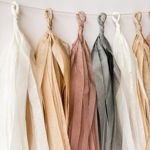 A close up of eight hand rolled tassels hanging from a string used for a boho party theme.