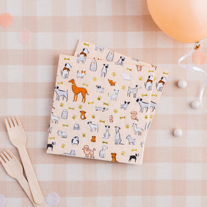 Cream colored napkin with multiple dogs on it and gold foil paw prints and bones.