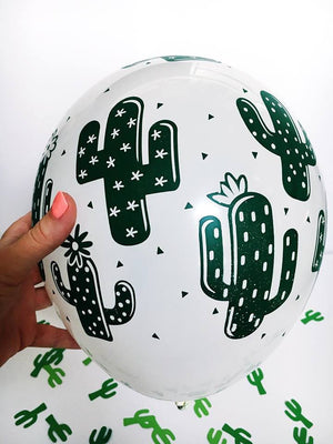 A zoomed in view of the white balloon with green cactus design is shown with little green cactus confetti scattered in the background.