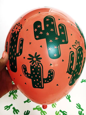 A zoomed in view of the coral balloon with green cactus design is shown with little green cactus confetti scattered in the background.