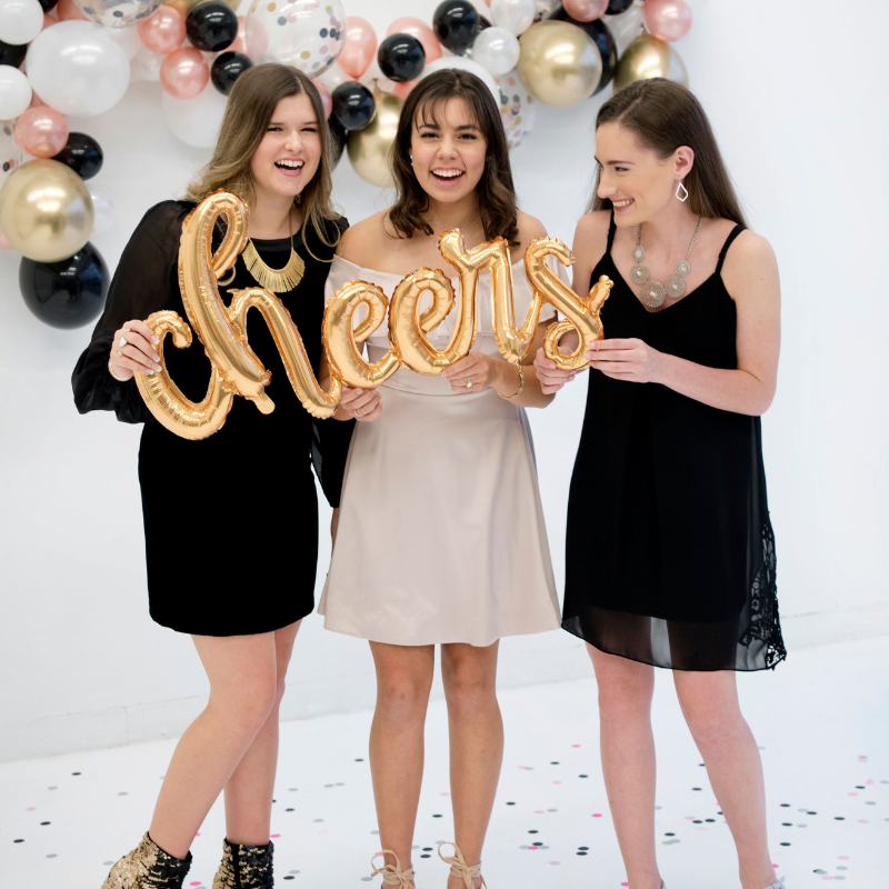 Three girls holding a 46" Gold Mylar "Cheers" Balloon