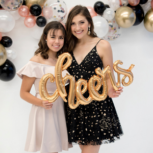 Two girls smiling holding a 46 inch gold mylar "cheers" balloon.