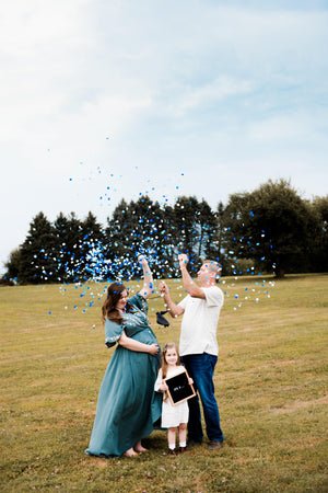 Gender reveal couple popping a 36 inch black latex balloon filled with shades of blue confetti.