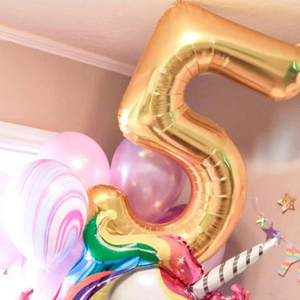 A gold 5 balloon in a bouquet of balloons that include a unicorn, marble print, and various pinks.