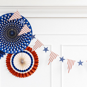 Red, white, and blue pendant and star banner hanging in front of a white wall.