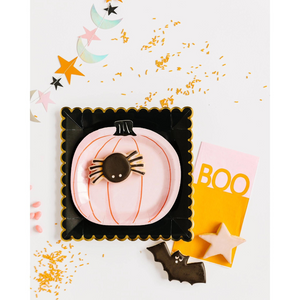 A Halloween Fall tablescape with pink pumpkin shaped plates, spider, bat, and star shaped sugar cookies, and orange sprinkles.