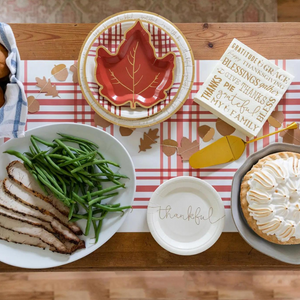 A Thanksgiving tablescape with white and gold plates that read thankful and grateful. 