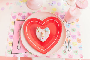 Pile of pastel colored hand cut tissue confetti paper on a pink table with a red paper plate at the center.