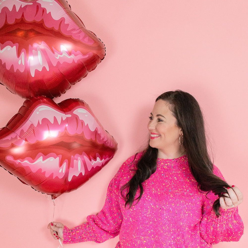 Woman holding two giant 30 inch lip balloons in the colors red and pink.