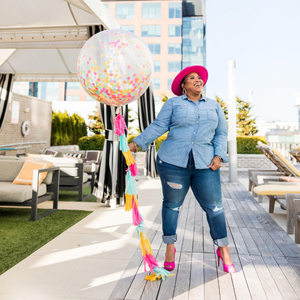 Woman smiling holding a jumbo 3ft clear balloon stuffed with tissue confetti.