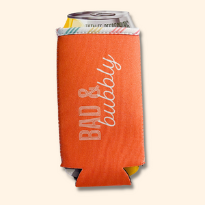 Orange colored can holder koozie reading BAD AND BUBBLY.