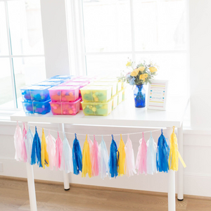 Hand rolled set of 20 tissue tassel garland hanging from a white table at a kids birthday party.