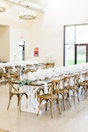 Close up of 20 foot white balloon garland with an assortment of 5 inch pearl white, white, and clear balloons sits as a centerpiece on a rustic wood table. Perfect for a bridal shower, wedding shower, boho baby shower, or wedding.