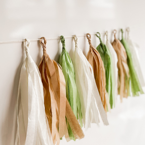 Close up of a set of 10 hand rolled tassels in the colors cream, tan, and sage.