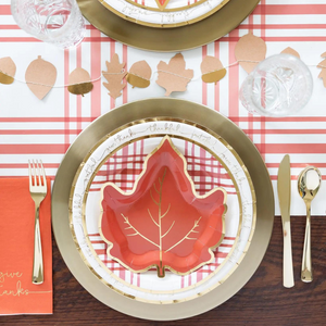 A beautiful thanksgiving tablescape with gold and orange plates. There are two gold chargers with thanksgiving themed plates sitting on top.