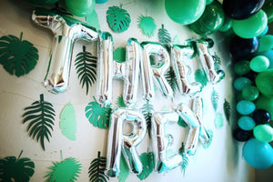 Close up of big silver letter balloons spelling THREE REX for a three year olds birthday party.