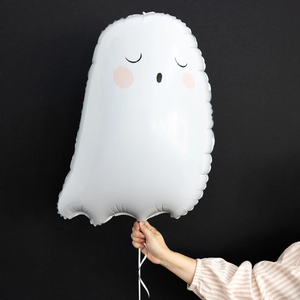 A womans hand is holding a white 26 inch ghost mylar balloon in front of a black wall.
