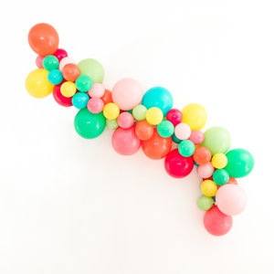 Assortment of balloons in the colors coral, wildberry, rose, pink, wintergreen, lime, caribbean blue, and yellow forming a balloon garland for a tropical party.