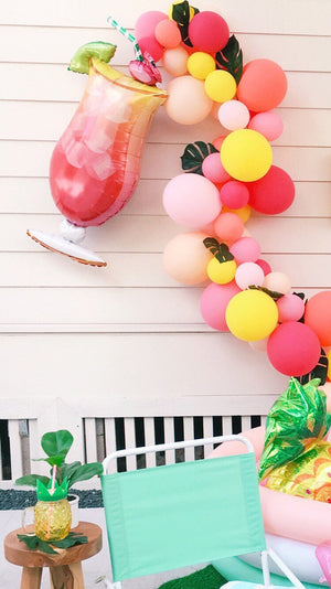 Jumbo 41 inch tropical drink balloon with a flamingo straw at the top followed by tropical theme balloon garland with paper palm leaves.