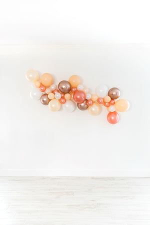 A zoomed in view shows a little more detail of a bridal themed balloon garland that is draped across a white wall.