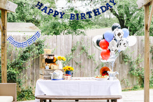 Two year olds birthday party in farm theme. There is a giant silver number tow balloon next to a bundle of black and white cow print balloons.