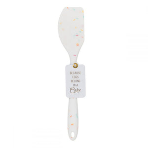 A silicone white confetti spatulas with a cute saying BECAUSE EGGS BELONG IN A CAKE.