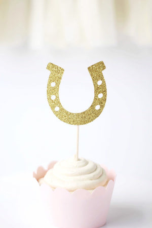 One gold glittery horseshoe topper on a white frosting cupcake.