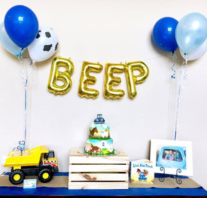 16 inch gold mylar balloons spelling BEEP for a boys birthday party. Two balloon bundles in different shades of blue sitting on a blue table.