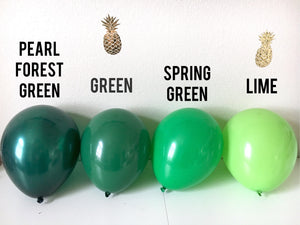 Four 11 inch latex balloons sit on a white floor with the colors pearl forest green, green, spring green, and lime.
