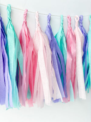 Front view of hand rolled tissue tassel garland in the colors pink, blush, lilac, and aqua used in mermaid or princess inspired birthday girl parties, unicorn parties or baby showers.