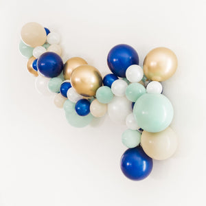 A side view of the nautical themed garland shows a little more depth and a different angle. The garland consists of various 5 inch and 11 inch balloons in the colors of pearl white, tan, jade, navy, and chrome gold.