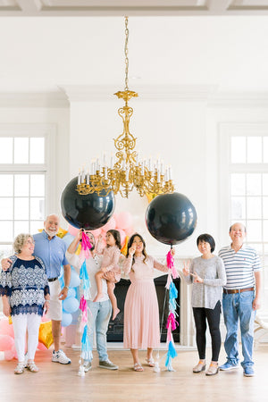 Family celebrating a gender reveal with a 36 inch black latex balloon filled with either shades of pink (GIRL) or shades of blue (BOY) confetti.