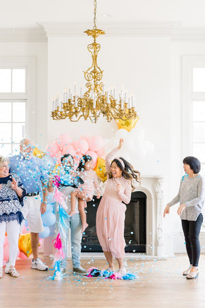 Family celebrating gender reveal after popping a 36 inch black latex balloon filled with shades of blue confetti.