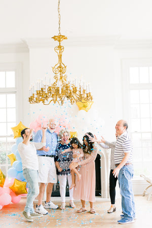 Family celebrating gender reveal after popping a 36 inch black latex balloon filled with shades of blue confetti.