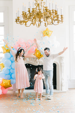 Family celebrating gender reveal after popping a 36 inch black latex balloon filled with shades of blue confetti.