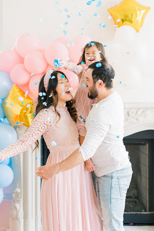 Couple hugging with gender reveal blue confetti falling on them.