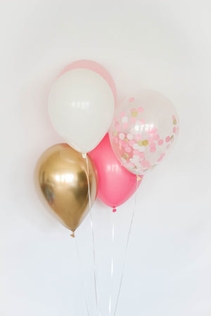 A pretty princess five balloon bundle with one pink, one rose, one white, one chrome gold, and one confetti filled balloon in front of a white wall.