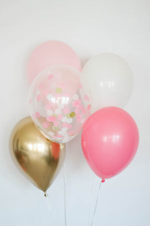 A princess balloon bundle with one pink, one rose, one white, one chrome gold, and one confetti filled balloon in front of a white wall.