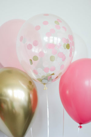 Close up of a chrome balloon, a pink balloon, a rose balloon, and a clear confetti filled balloon.